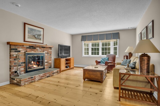 35 Whitethorn Dr, Guilford, CT 06437 - living room featuring baseboard heating, wood-type flooring, a textured ceiling, a brick fireplace, and baseboards