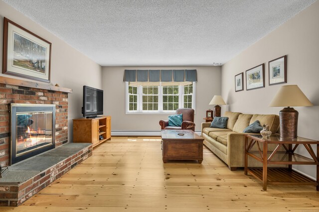 35 Whitethorn Dr, Guilford, CT 06437 - living area with a baseboard radiator, a brick fireplace, a textured ceiling, and wood-type flooring