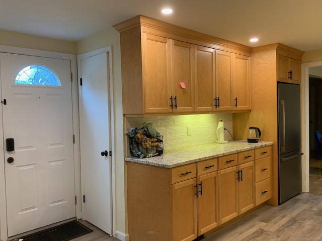92 Jones Dr, New Britain, CT 06053 - kitchen with freestanding refrigerator, light wood-type flooring, recessed lighting, decorative backsplash, and light stone counters