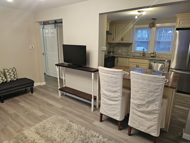 262 Meyer Rd, Torrington, CT 06790 - kitchen featuring stainless steel appliances, a barn door, light wood-style floors, tasteful backsplash, and under cabinet range hood
