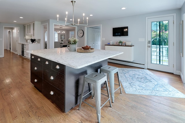 29 Bayberry Rd, Fairfield, CT 06825 - kitchen with a baseboard radiator, a chandelier, white cabinetry, a kitchen island, and light wood-type flooring
