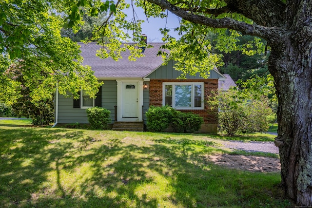 824 Torringford W St, Torrington, CT 06790 - cape cod-style house featuring brick siding, a front yard, a shingled roof, entry steps, and board and batten siding