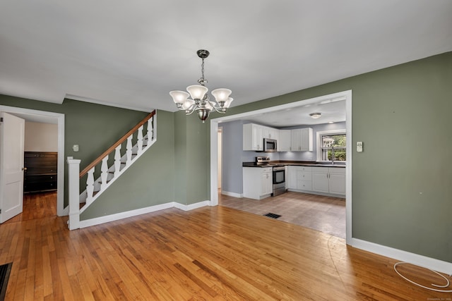 824 Torringford W St, Torrington, CT 06790 - unfurnished dining area featuring a chandelier, light wood-style floors, and stairs