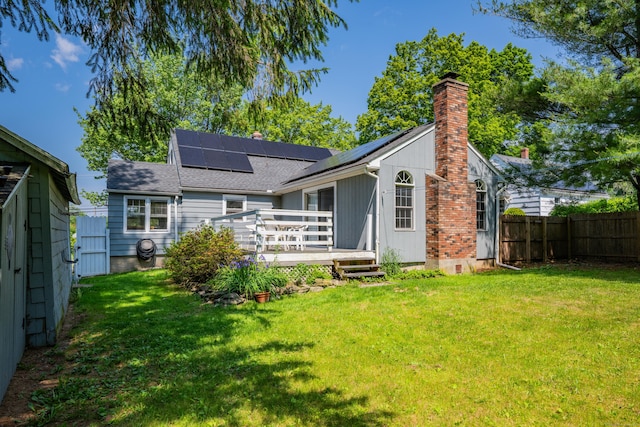 824 Torringford W St, Torrington, CT 06790 - back of house featuring a chimney, a deck, a fenced backyard, and roof mounted solar panels