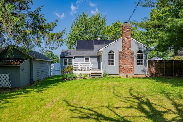 824 Torringford W St, Torrington, CT 06790 - rear view of property featuring a chimney, solar panels, a deck, a shed, and a shingled roof