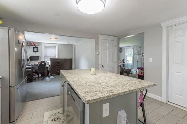 12 John St, Killingly, CT 06239 - kitchen with freestanding refrigerator, a desk, a center island, a breakfast bar, and light stone countertops