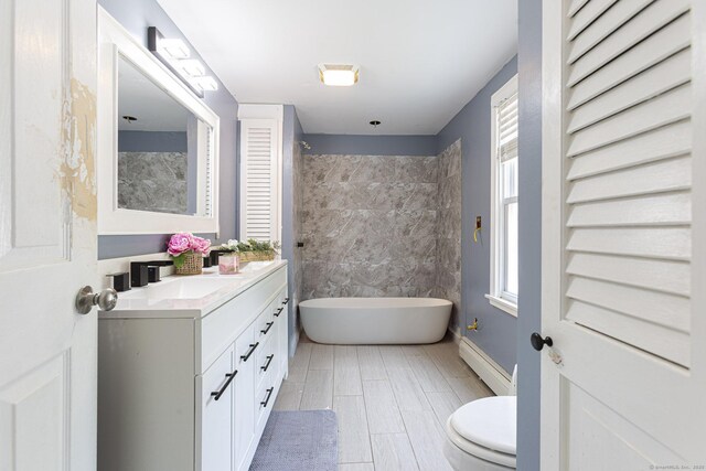 12 John St, Killingly, CT 06239 - full bathroom featuring a soaking tub, vanity, toilet, a baseboard heating unit, and wood finished floors