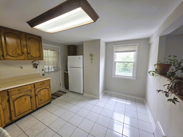 149 Branford St, Manchester, CT 06040 - kitchen featuring freestanding refrigerator, brown cabinetry, light countertops, and light tile patterned floors