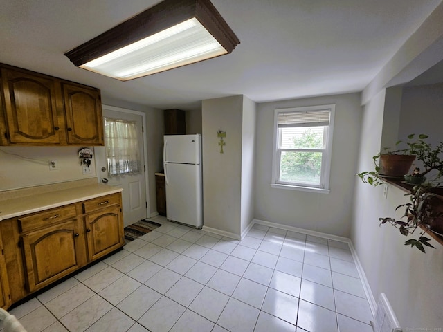 149 Branford St, Manchester, CT 06040 - kitchen with freestanding refrigerator, light countertops, brown cabinetry, and light tile patterned floors
