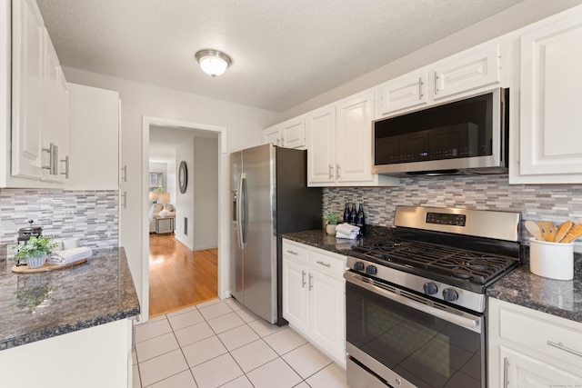 75 Brittania Rd Unit 75, Danbury, CT 06811 - kitchen with appliances with stainless steel finishes, white cabinets, light tile patterned floors, decorative backsplash, and dark stone counters