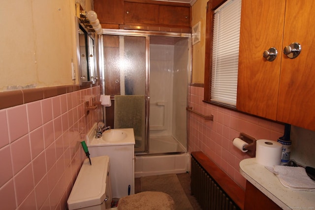 87 Hayden St, Windham, CT 06226 - bathroom with tile walls, radiator heating unit, toilet, a sink, and combined bath / shower with glass door