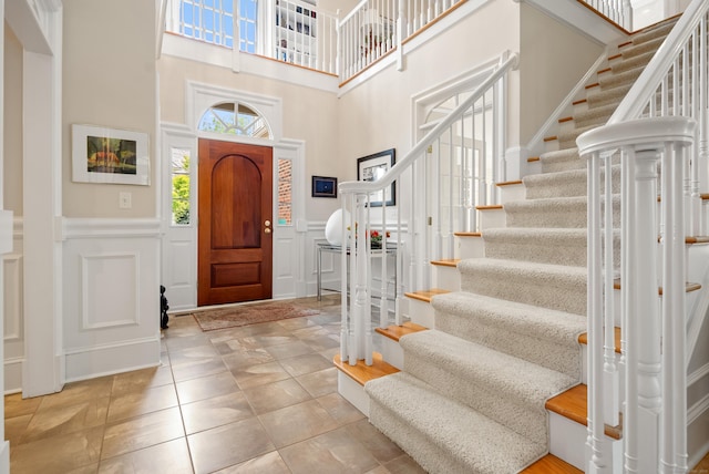 184 Stillson Rd Unit 184, Fairfield, CT 06825 - tiled foyer with a decorative wall, stairway, a wainscoted wall, and a towering ceiling