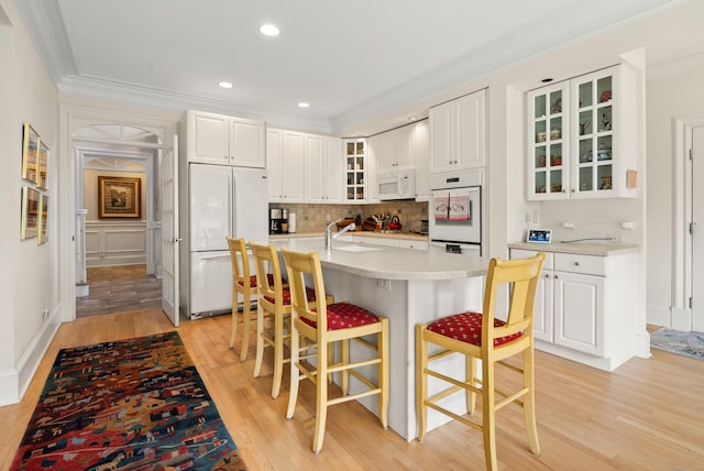 184 Stillson Rd Unit 184, Fairfield, CT 06825 - kitchen with white appliances, light wood-style flooring, a kitchen breakfast bar, crown molding, and glass insert cabinets