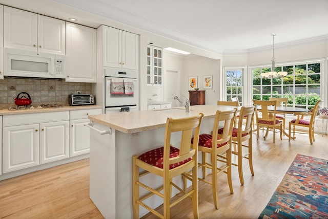 184 Stillson Rd Unit 184, Fairfield, CT 06825 - kitchen featuring white appliances, crown molding, backsplash, a breakfast bar area, and light wood finished floors