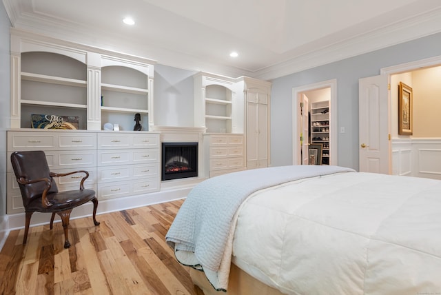184 Stillson Rd Unit 184, Fairfield, CT 06825 - bedroom with ornamental molding, light wood-style floors, a spacious closet, recessed lighting, and a warm lit fireplace
