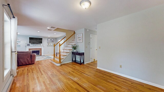 19 Heritage Brook Dr, East Haddam, CT 06423 - unfurnished living room with stairs, a baseboard radiator, a fireplace, and light wood-style floors