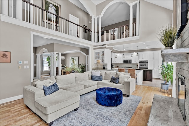 18 Cedar Spring Rd, Burlington, CT 06013 - living room featuring ornate columns, light wood-style flooring, arched walkways, a high ceiling, and baseboards
