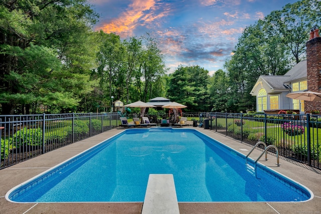18 Cedar Spring Rd, Burlington, CT 06013 - pool at dusk featuring a diving board, view of scattered trees, and a patio