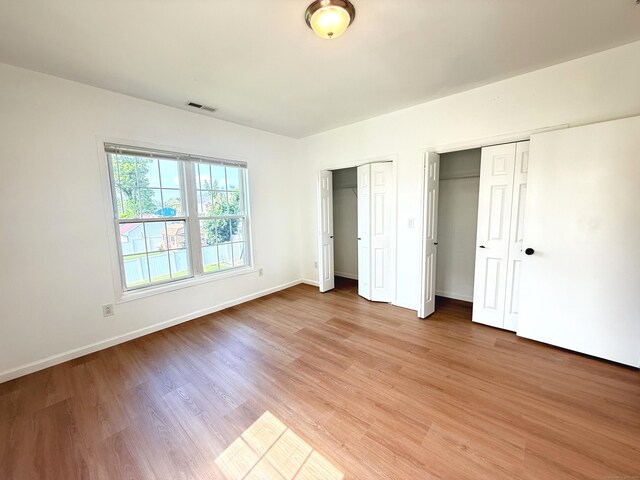 53 Cosey Beach Rd, East Haven, CT 06512 - unfurnished bedroom with two closets, light wood finished floors, and baseboards