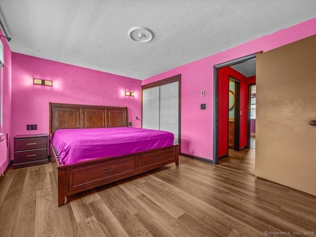 1081 New Haven Rd Apt 12F, Naugatuck, CT 06770 - bedroom featuring wood finished floors, a closet, a textured ceiling, and baseboards