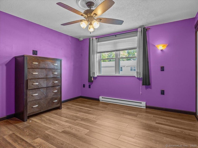 1081 New Haven Rd Apt 12F, Naugatuck, CT 06770 - unfurnished bedroom featuring a baseboard heating unit, wood finished floors, a textured ceiling, baseboards, and ceiling fan