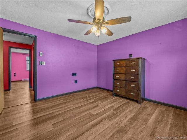 1081 New Haven Rd Apt 12F, Naugatuck, CT 06770 - unfurnished bedroom featuring wood finished floors, baseboard heating, baseboards, a textured ceiling, and a ceiling fan
