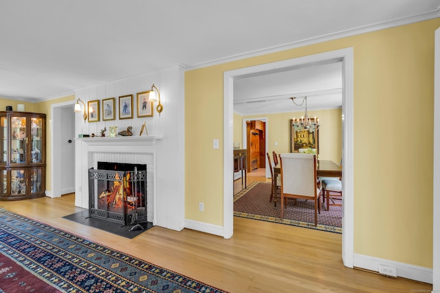 171 Still Rd, West Hartford, CT 06117 - living room featuring wood finished floors, a brick fireplace, ornamental molding, and a chandelier