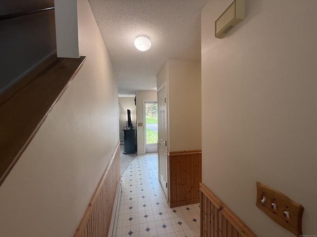 24 Podunk Cir Unit 24, South Windsor, CT 06074 - hall featuring a wainscoted wall, a textured ceiling, light flooring, and wood walls