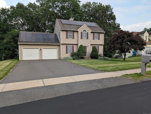 190 Sunnydale Ave, Bristol, CT 06010 - colonial-style house featuring roof mounted solar panels, an attached garage, a front lawn, asphalt driveway, and a standing seam roof