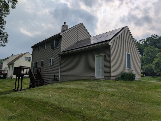 190 Sunnydale Ave, Bristol, CT 06010 - rear view of property featuring a chimney, solar panels, a lawn, a deck, and stairs