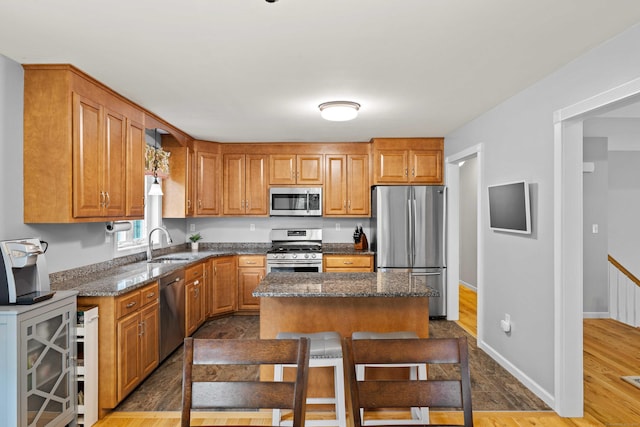 43 Old Young St, East Hampton, CT 06424 - kitchen with appliances with stainless steel finishes, dark stone countertops, a kitchen island, brown cabinets, and a breakfast bar area