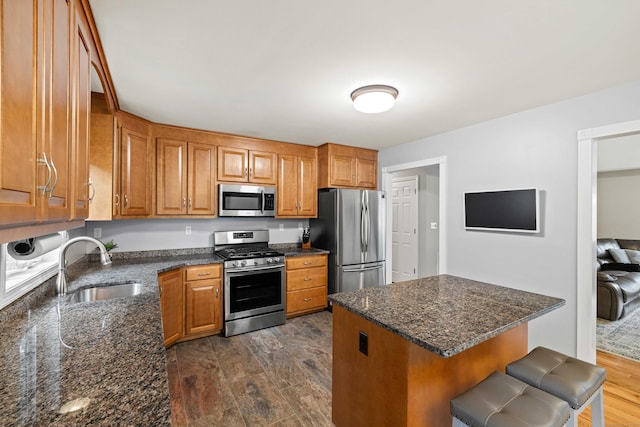 43 Old Young St, East Hampton, CT 06424 - kitchen with appliances with stainless steel finishes, brown cabinets, dark stone counters, a kitchen bar, and a center island