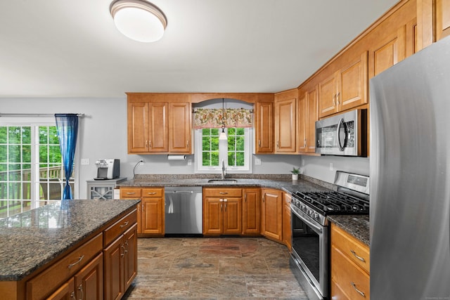 43 Old Young St, East Hampton, CT 06424 - kitchen with appliances with stainless steel finishes, stone finish flooring, brown cabinets, dark stone countertops, and a center island
