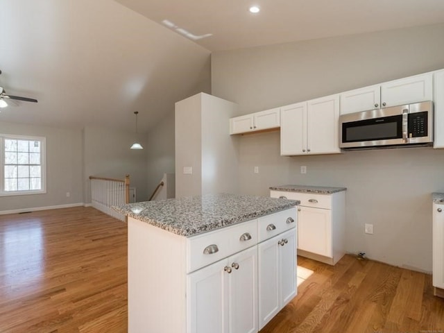 12 S St, Brooklyn, CT 06234 - kitchen with stainless steel microwave, light wood-style floors, light stone counters, lofted ceiling, and ceiling fan