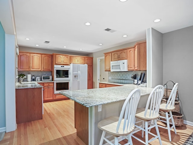 52 Grumman Ave, Wilton, CT 06897 - kitchen featuring white appliances, a peninsula, backsplash, light stone countertops, and recessed lighting