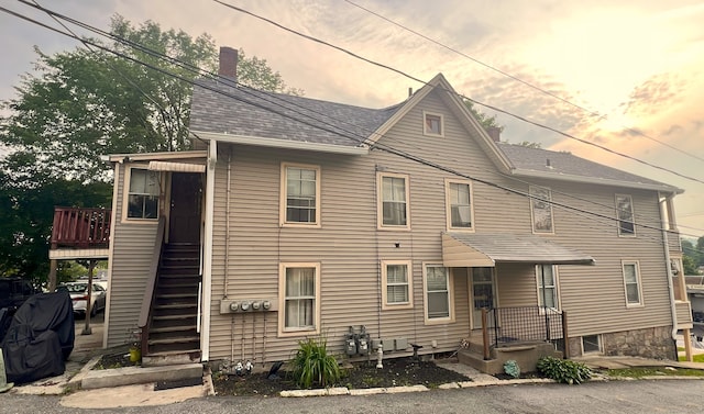 238 E Main St, Torrington, CT 06790 - back of property at dusk featuring a chimney, stairway, and a shingled roof