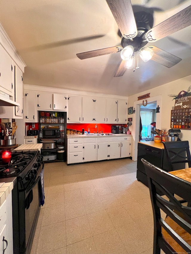 238 E Main St, Torrington, CT 06790 - kitchen with stainless steel gas range, white cabinetry, ceiling fan, under cabinet range hood, and tile countertops