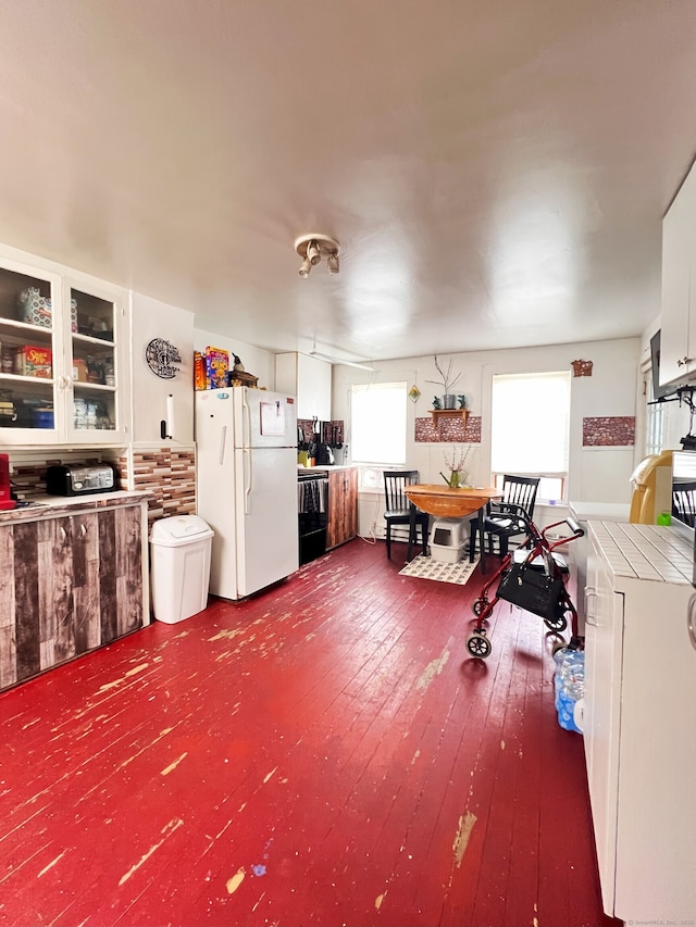 238 E Main St, Torrington, CT 06790 - kitchen with freestanding refrigerator, black electric range, tile counters, dark wood-type flooring, and glass insert cabinets