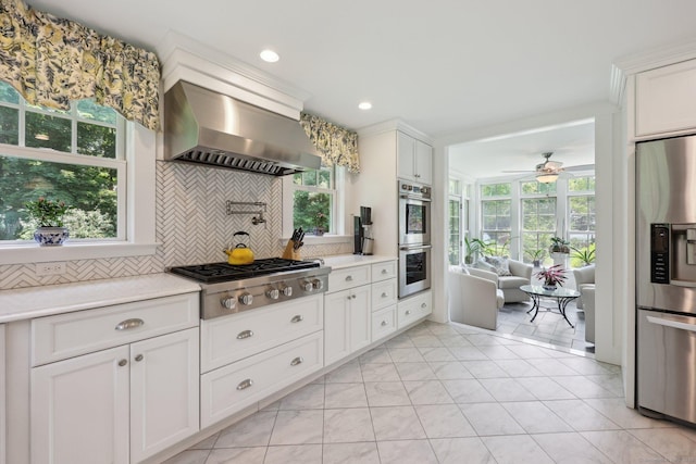 2200 Ridge Rd, North Haven, CT 06473 - kitchen featuring appliances with stainless steel finishes, wall chimney range hood, backsplash, light countertops, and ceiling fan
