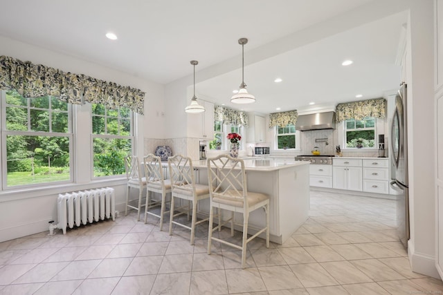 2200 Ridge Rd, North Haven, CT 06473 - kitchen with radiator heating unit, wall chimney range hood, a peninsula, appliances with stainless steel finishes, and recessed lighting