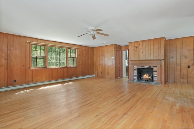 130 Sturbridge Ln, Fairfield, CT 06890 - unfurnished living room featuring a baseboard radiator, light wood-type flooring, ceiling fan, wooden walls, and a brick fireplace