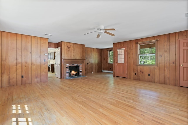 130 Sturbridge Ln, Fairfield, CT 06890 - unfurnished living room featuring light wood finished floors, a ceiling fan, a baseboard radiator, wood walls, and a fireplace