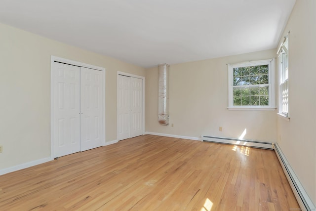 130 Sturbridge Ln, Fairfield, CT 06890 - unfurnished bedroom featuring a baseboard heating unit, a baseboard radiator, multiple closets, and light wood-style flooring