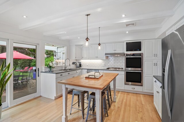 86 Lorma Ave, Trumbull, CT 06611 - kitchen featuring stainless steel appliances, light wood-style floors, decorative backsplash, white cabinets, and beam ceiling