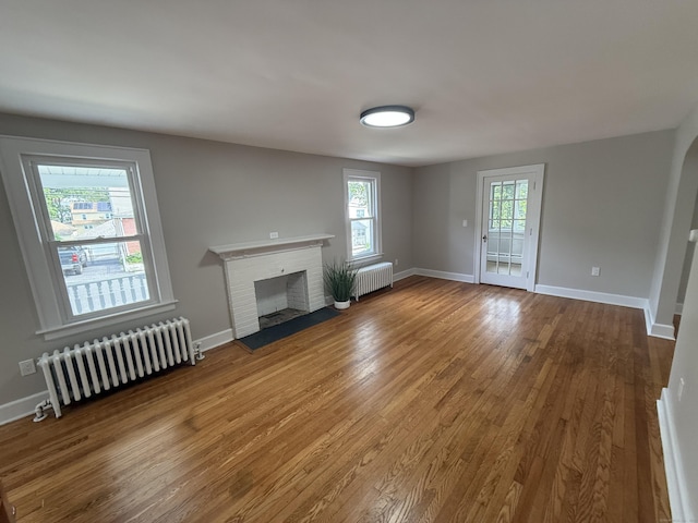 28 Highland Ave, Naugatuck, CT 06770 - unfurnished living room with radiator heating unit, wood finished floors, and a brick fireplace