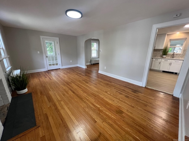 28 Highland Ave, Naugatuck, CT 06770 - unfurnished living room featuring arched walkways, wood finished floors, radiator, and healthy amount of natural light
