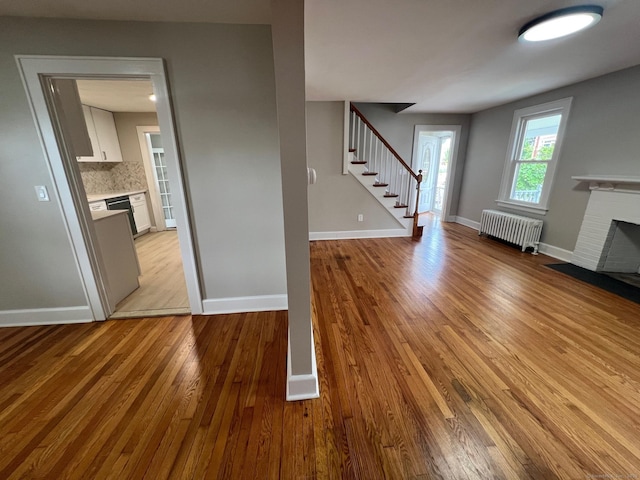 28 Highland Ave, Naugatuck, CT 06770 - unfurnished living room featuring a fireplace, radiator heating unit, stairway, and light wood-style flooring