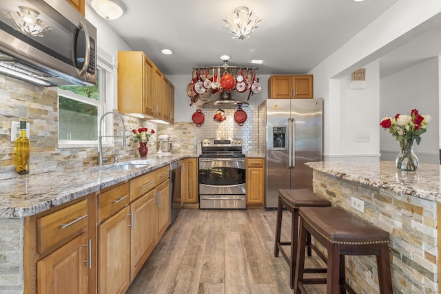 408 Stage Coach Rd, Durham, CT 06422 - kitchen with appliances with stainless steel finishes, light wood-style floors, backsplash, light stone counters, and a breakfast bar