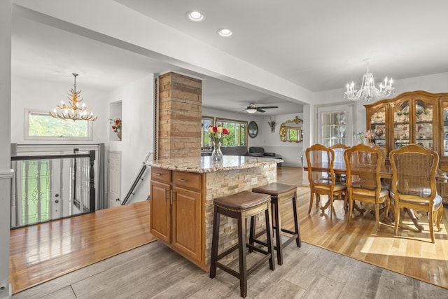 408 Stage Coach Rd, Durham, CT 06422 - kitchen with a chandelier, light wood-style floors, brown cabinetry, light stone countertops, and a breakfast bar