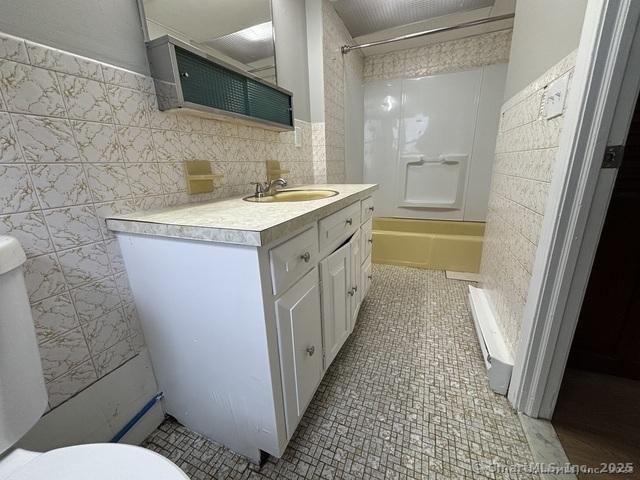 25 W Coit St, New London, CT 06320 - bathroom featuring tile walls, toilet, vanity, tub / shower combination, and tile patterned floors